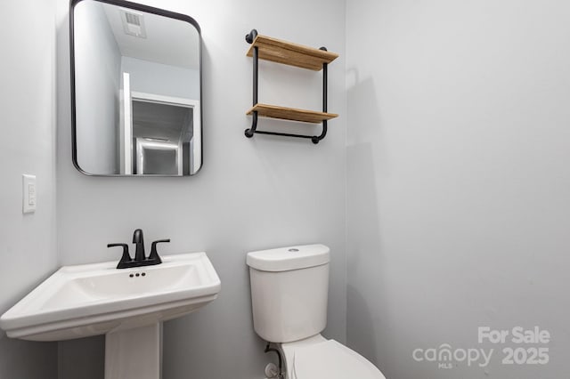 half bath with visible vents, a sink, and toilet