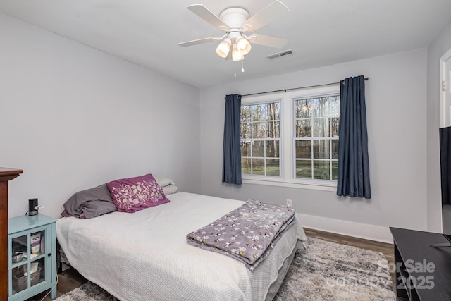 bedroom with baseboards, ceiling fan, visible vents, and wood finished floors