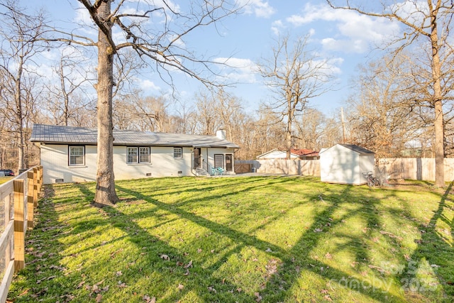 view of yard featuring a storage shed, a fenced backyard, and an outbuilding