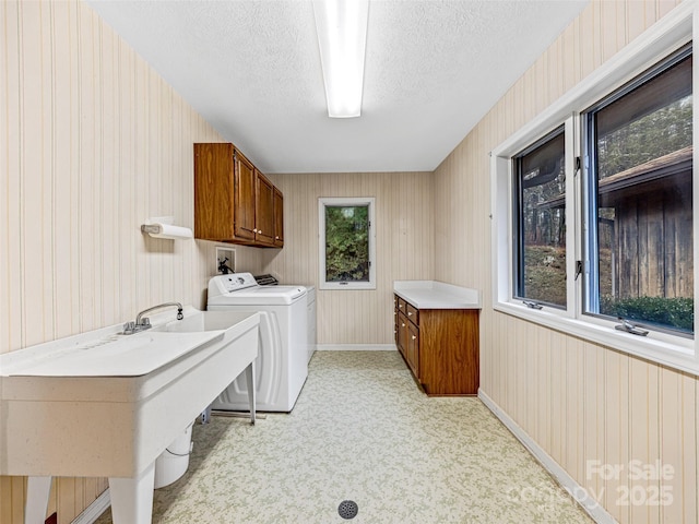 laundry room featuring cabinets, light colored carpet, sink, washer and dryer, and a textured ceiling