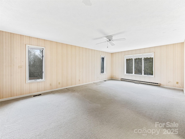 carpeted empty room featuring ceiling fan and a baseboard heating unit