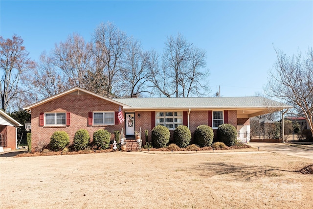 ranch-style home featuring an attached carport, concrete driveway, brick siding, and a chimney