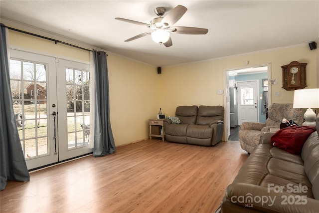 living area featuring light wood-style floors, plenty of natural light, ornamental molding, and french doors