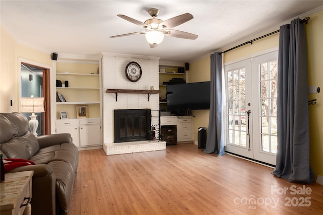 living area with light wood-type flooring, crown molding, a wealth of natural light, and french doors