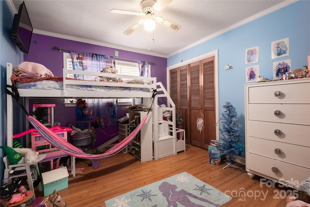 bedroom with a textured ceiling, a closet, wood finished floors, and crown molding