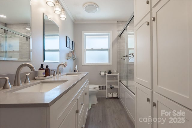 full bath with crown molding, combined bath / shower with glass door, a sink, and wood finished floors