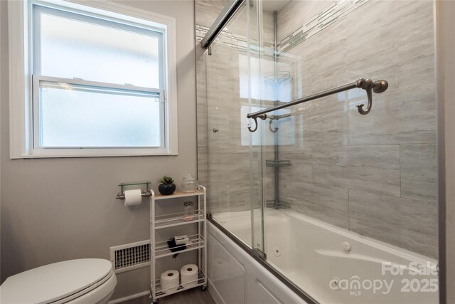 bathroom featuring shower / bath combination with glass door and toilet