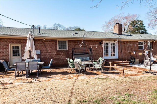 back of property featuring french doors, a patio area, brick siding, and a chimney