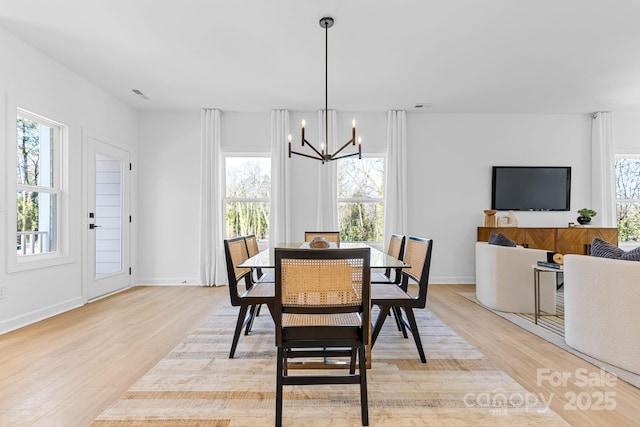 dining area with light hardwood / wood-style flooring and a notable chandelier