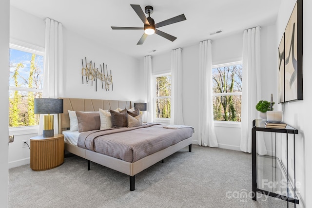 bedroom featuring multiple windows, light carpet, and ceiling fan