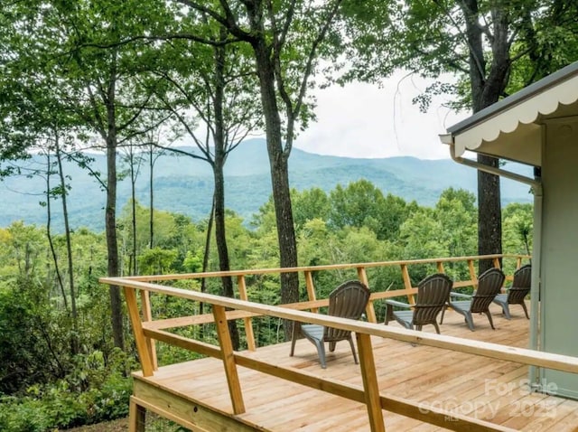 deck with a wooded view and a mountain view