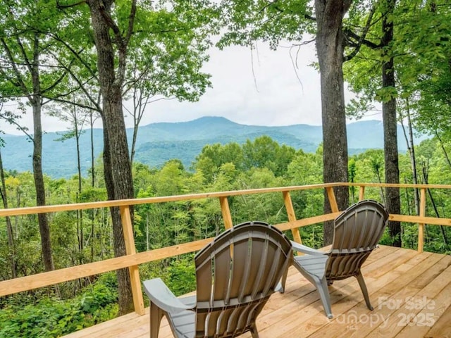 exterior space featuring a wooded view and a deck with mountain view