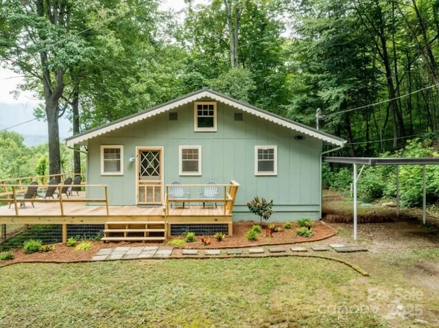 back of property featuring a carport, board and batten siding, a wooden deck, and a lawn
