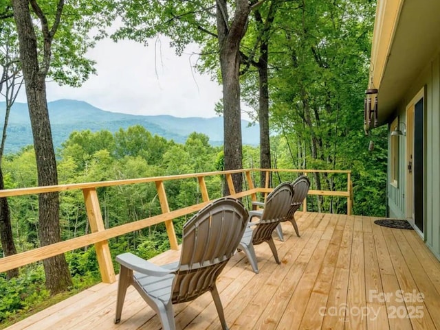 wooden deck with a mountain view and a view of trees