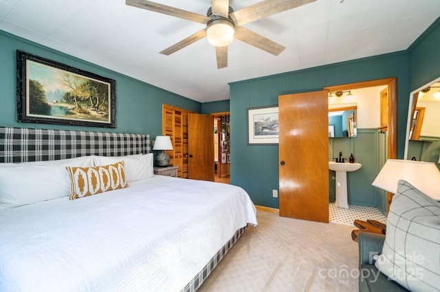 carpeted bedroom with ensuite bathroom and ceiling fan