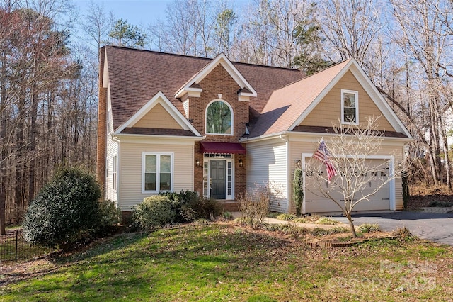 view of front facade featuring driveway, a shingled roof, an attached garage, a front yard, and brick siding