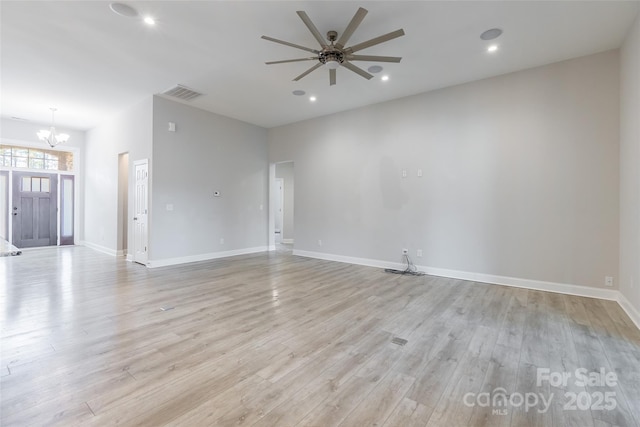 empty room with recessed lighting, visible vents, light wood-type flooring, baseboards, and ceiling fan with notable chandelier