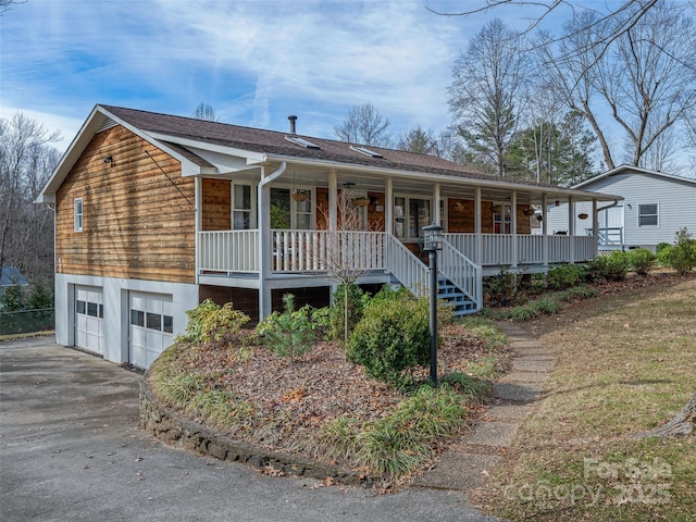 view of front of home featuring covered porch, a garage, a shingled roof, stairs, and driveway