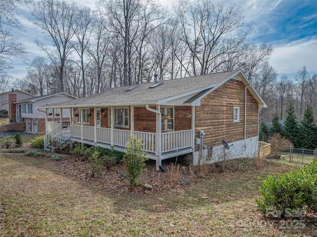 view of front of property with covered porch, a shingled roof, and a front lawn