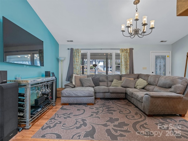 living area featuring visible vents, light wood-style flooring, and an inviting chandelier