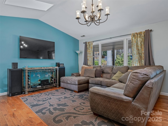 living area with vaulted ceiling with skylight, visible vents, baseboards, and wood finished floors