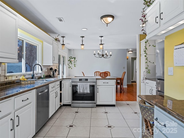 kitchen with stainless steel appliances, dark countertops, white cabinetry, and visible vents