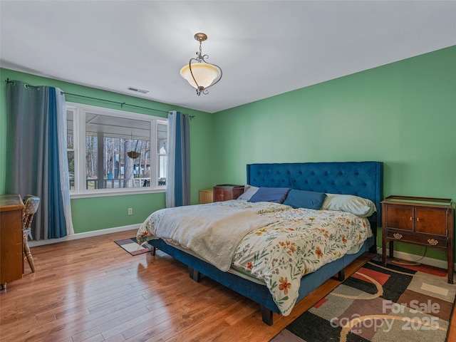 bedroom with visible vents, baseboards, and wood finished floors