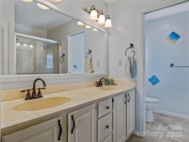 full bath featuring toilet, a stall shower, double vanity, and a sink