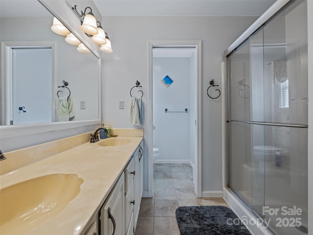 full bathroom featuring double vanity, a stall shower, toilet, and a sink