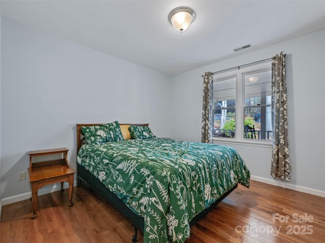 bedroom featuring wood finished floors, visible vents, and baseboards