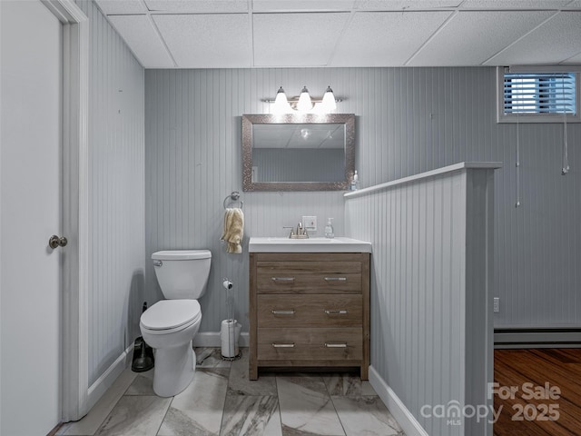 bathroom with marble finish floor, a drop ceiling, vanity, and toilet