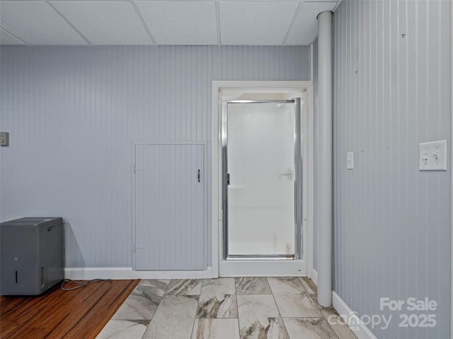 interior space with marble finish floor, a paneled ceiling, and baseboards