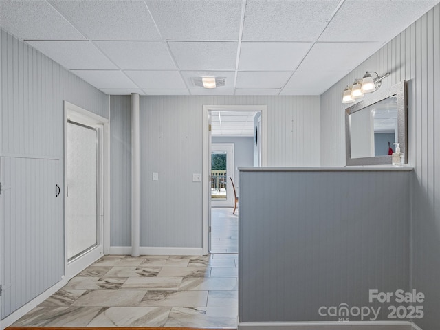 corridor with a paneled ceiling, marble finish floor, and visible vents