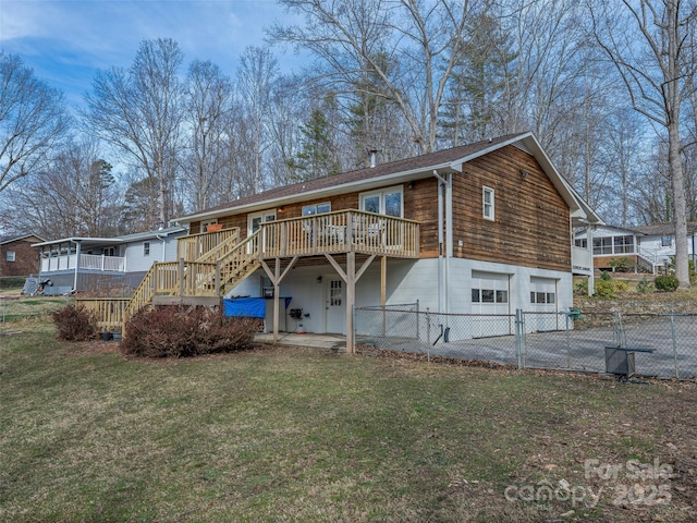 back of house with driveway, a lawn, an attached garage, fence, and a wooden deck