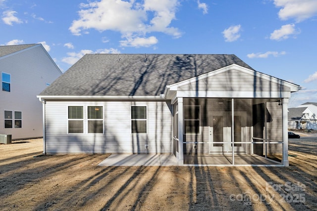 rear view of property with central AC, roof with shingles, a patio area, and a sunroom