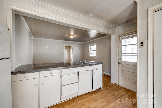 kitchen with white cabinets, light hardwood / wood-style floors, sink, and ornamental molding