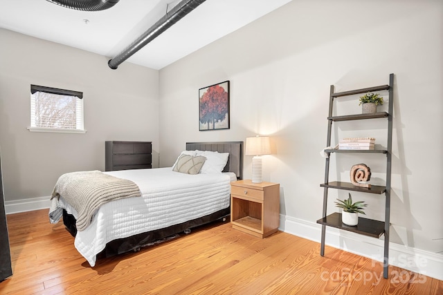 bedroom featuring wood-type flooring and beamed ceiling