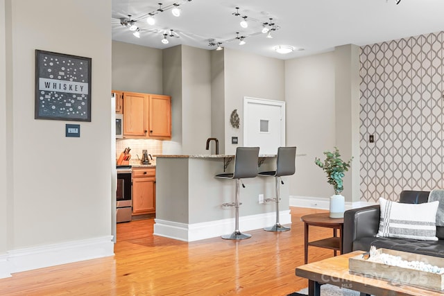 kitchen with light wood-type flooring, tasteful backsplash, a breakfast bar area, and stainless steel appliances