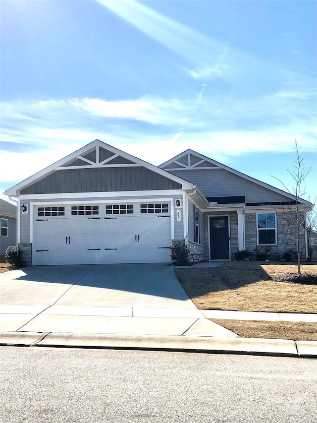 view of front of home featuring stone siding, an attached garage, and concrete driveway