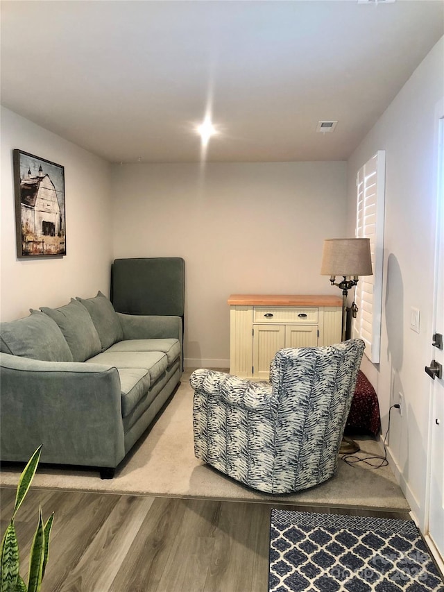 living area featuring visible vents, light wood-style flooring, and baseboards