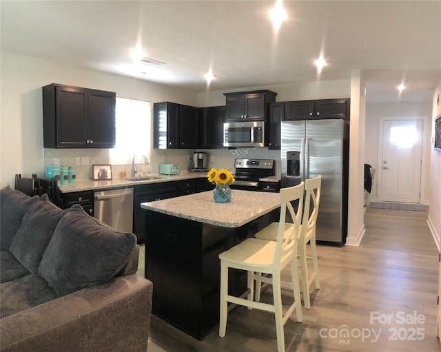 kitchen with light wood-style flooring, appliances with stainless steel finishes, open floor plan, a breakfast bar, and a center island