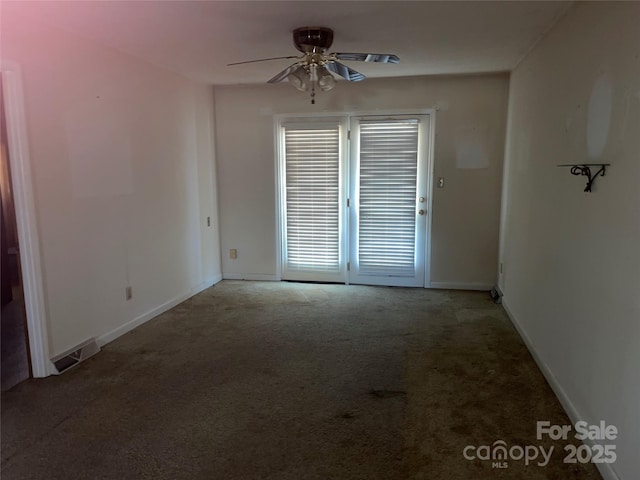 carpeted empty room featuring a ceiling fan, visible vents, and baseboards