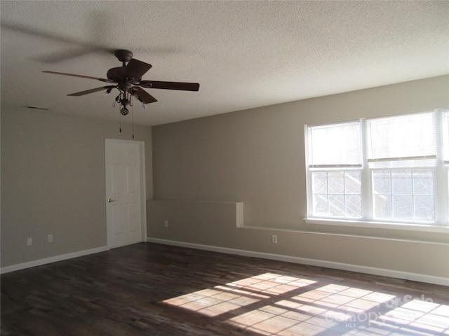 spare room featuring dark hardwood / wood-style flooring, a textured ceiling, and a wealth of natural light