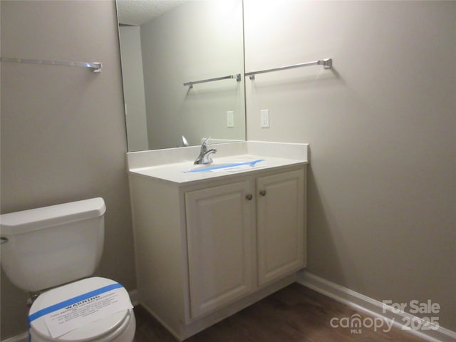 bathroom with wood-type flooring, vanity, and toilet