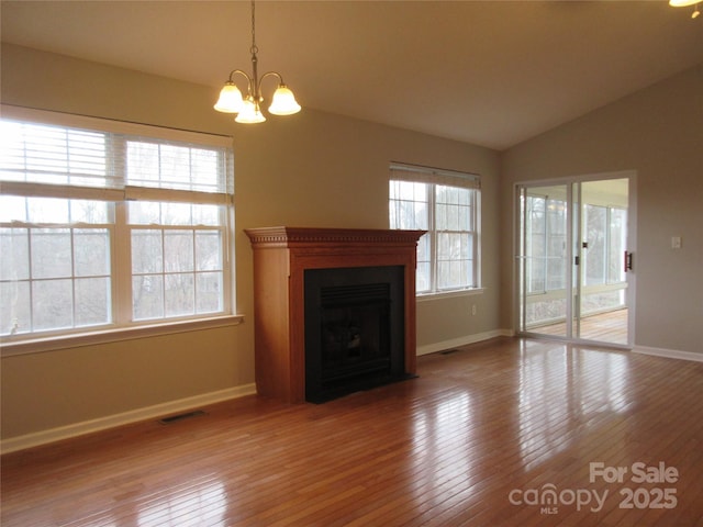 unfurnished living room featuring lofted ceiling, a chandelier, and hardwood / wood-style floors