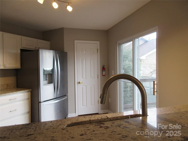 kitchen featuring white cabinetry, sink, light stone countertops, and stainless steel fridge with ice dispenser