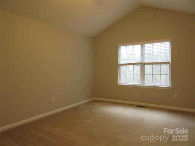 unfurnished room with vaulted ceiling and carpet flooring