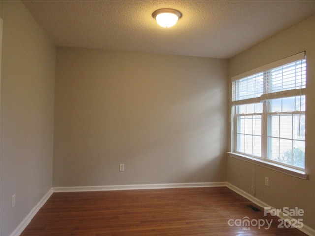 unfurnished room with dark hardwood / wood-style flooring and a textured ceiling