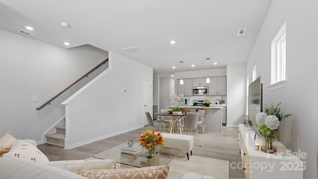 living area featuring light wood-style floors, stairs, visible vents, and recessed lighting