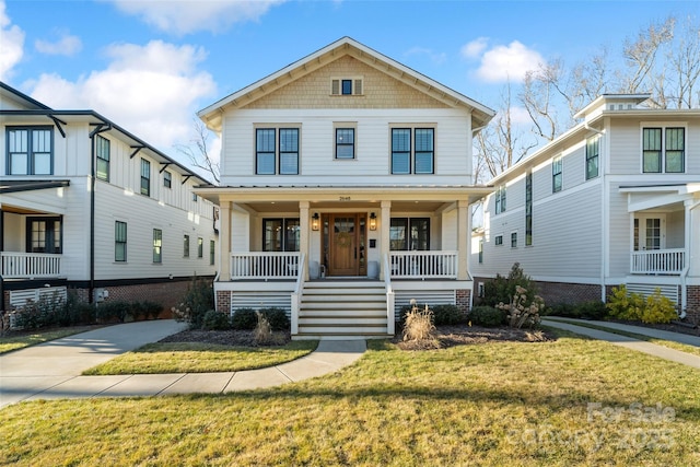 american foursquare style home featuring covered porch and a front lawn